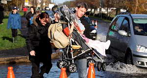 A man helps a young mother and her child through flood waters at Gort Road in Ennis. A man helps a young mother and her child through flood waters at Gort Road in Ennis.