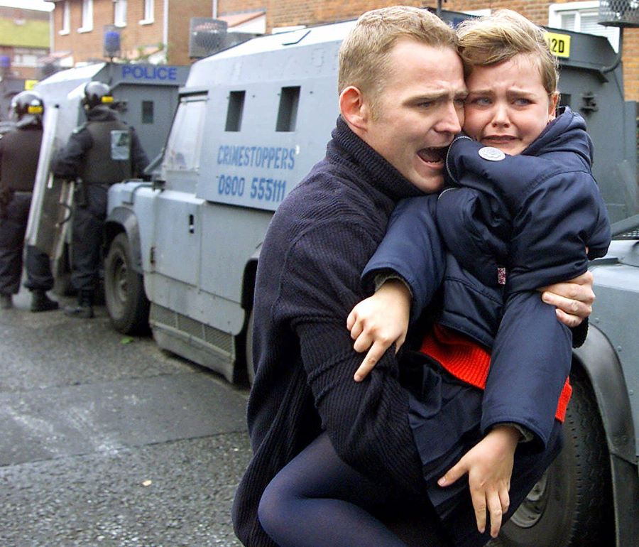 David Lindsay carries his daughter Amy after a blast bomb exploded as they made their way to Holy Cross school in north Belfast, in September