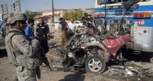 A US Army soldier and Iraqi police stand at the site of a bombing in Kirkuk.