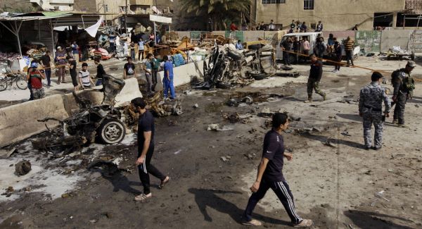 Iraqis inspect the scene of a car bomb attack in the Ameen neighborhood in eastern Baghdad