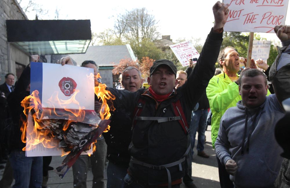 Anti-austerity protesters burn literature outside the conference.