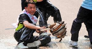 One of two North Korean defectors Son Jong Hoon pours gasoline as police officers try to detain them during the Beijing Olympic torch run in Seoul, South Korea, today.