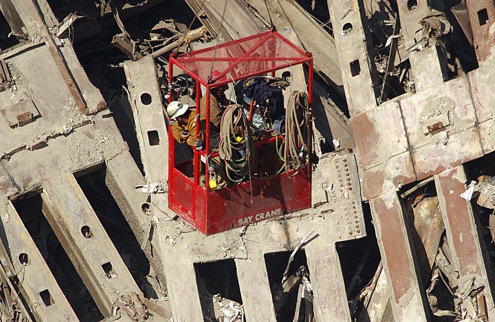 Workers being lowered by a crane examine the rubble at the site of the twin towers, about 10 days after the attacks. Picture: AP