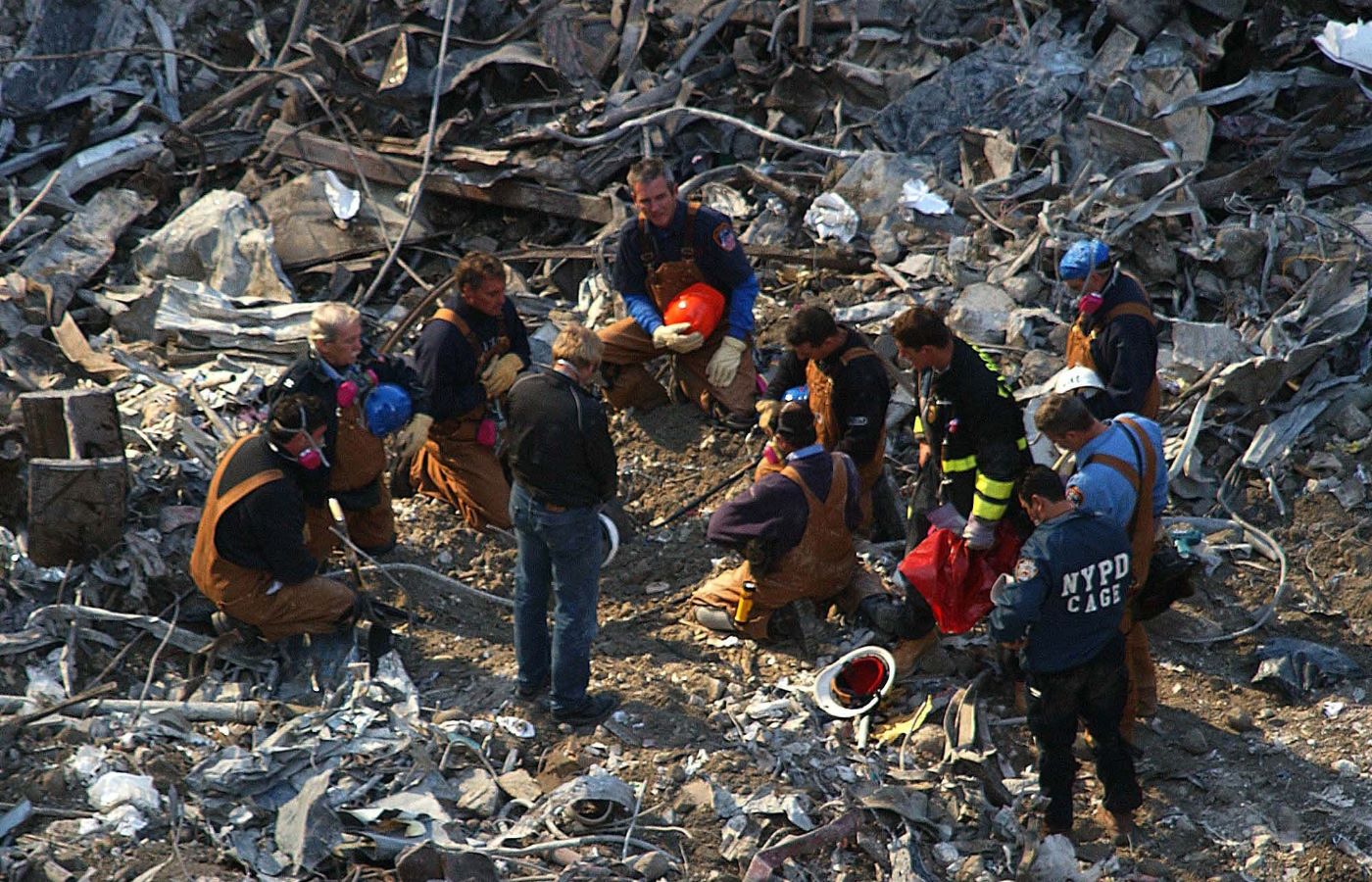 Rescue workers remove their hats and bow their heads in the rubble of the World Trade Centre.